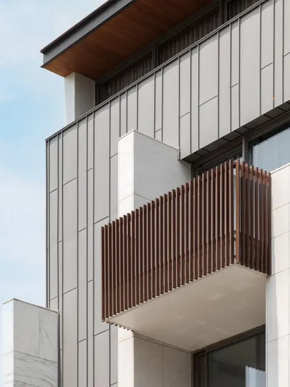 A detail shot of the facade, showing the precise placement of zinc panels against the stone and the clean lines of the balcony. Every material is chosen and applied to contribute to the overall architectural harmony.