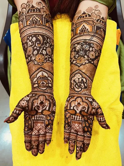 A stunning floral and architectural design. This mehndi combines the softness of rose patterns with the grandeur of palace domes, along with peacock figures on the palms.