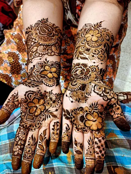 This bridal design is rich with bold flowers and delicate filler patterns, covering the hands and wrists.