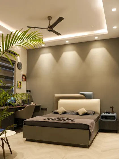 This rustic-elegant bedroom in the Monochrome Oasis project features a grey color theme with a unique asymmetrical headboard and a dedicated study area.
