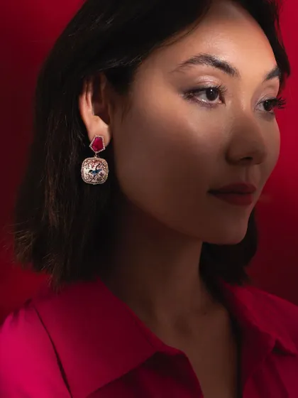 A model wearing the Sakura inspired micromosaic earrings. The design, featuring a bird among cherry blossoms, is complemented by the deep red of the ruby tops, creating an enchanting look.