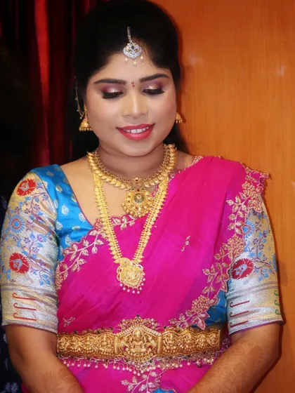 Sowmya looking beautiful for her engagement ceremony. Her makeup is kept classic and clean to complement her bright pink and blue silk saree and traditional gold jewelry.