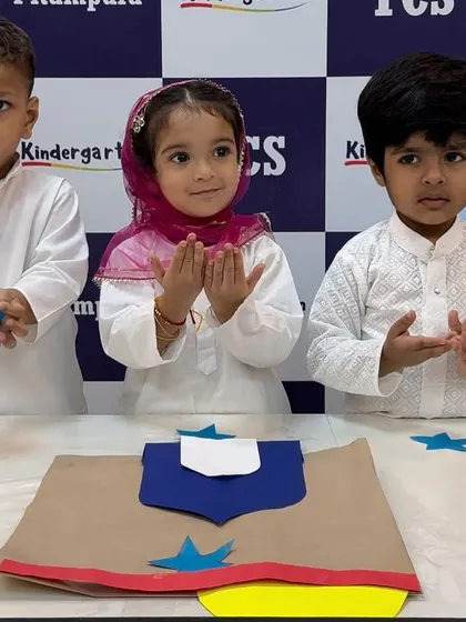 Three little ones proudly present their finished Eid craft. This activity not only enhances their creativity but also their understanding of the festival.
