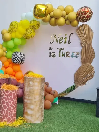 A modern and stylish take on a jungle theme for Neil's third birthday. The circular backdrop with gold lettering and animal-print balloons creates a chic safari look.