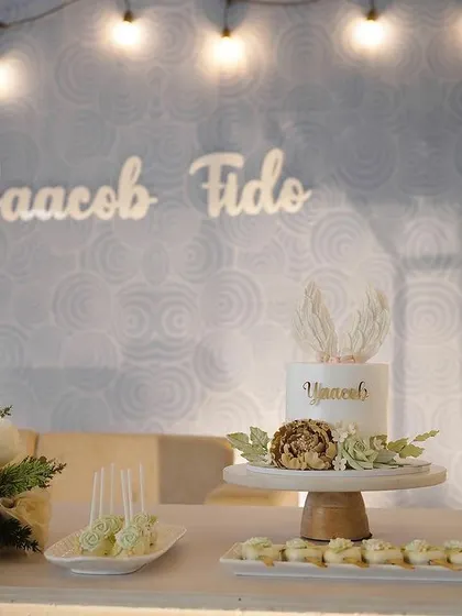 An elegant dessert table for a baptism ceremony. The setup includes a custom cake, cupcakes, and other small treats, all coordinated with the event's theme and color scheme.