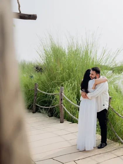 A candid and intimate embrace on a wooden bridge, framed by the natural surroundings.