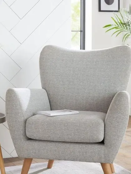A stylish and comfortable armchair in a light grey fabric with wooden legs. This piece of bespoke furniture is perfect for creating a cozy reading nook in a living room or bedroom.