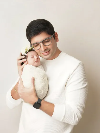 A father holds his swaddled newborn close, a picture of gentle strength and love. These father-child portraits are always a favorite.
