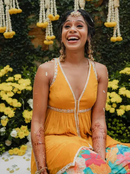 A radiant bride enjoying her Haldi ceremony. The bright orange and floral patiala, paired with gota jewelry, created a look that was full of life and perfect for the occasion.