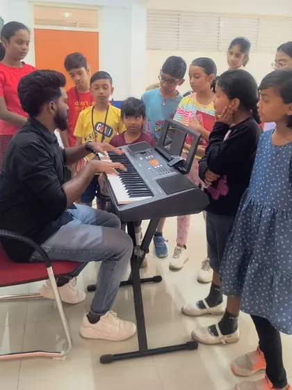 A group of curious students gathers around the keyboard for a music lesson, learning about melody and rhythm.