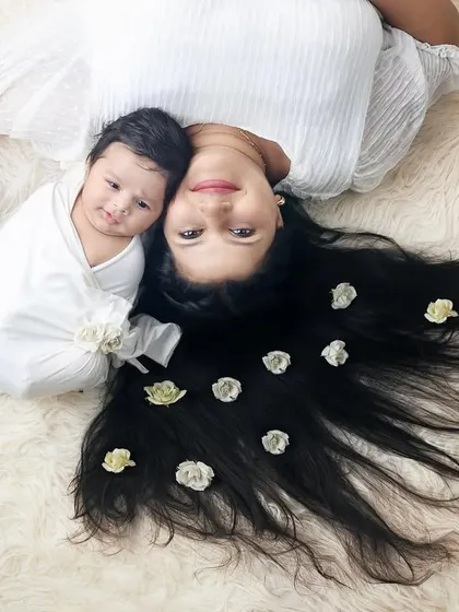 A creative and loving portrait of a mother and her newborn. Her hair, adorned with flowers, beautifully frames her precious baby.