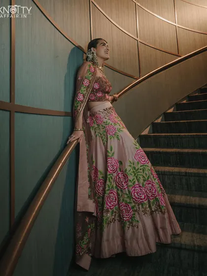 An elegant bridal portrait on a spiral staircase, showcasing the beautiful floral embroidery on her lehenga.
