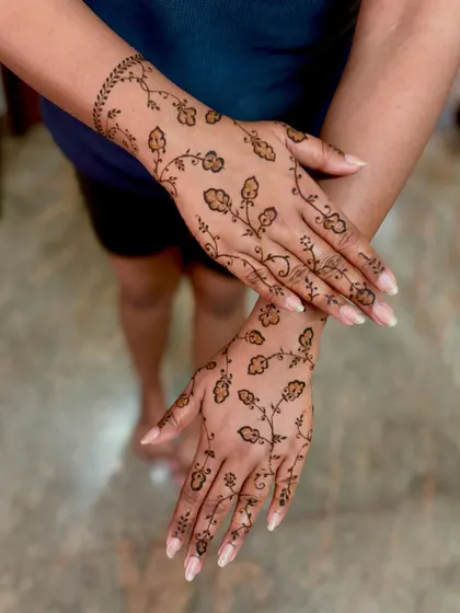 A delicate and unique design with floral vines scattered across the back of the hands, perfect for a reception or party.