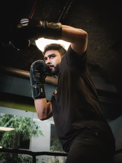 A focused shot of a client ready to strike during a boxing session. The intensity in his eyes shows the mental and physical engagement required for the sport.