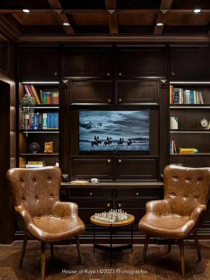 The library in 'Mina Nivas' was designed to feel like a moody, opulent English den. It features Chesterfield-style chairs, a waffle ceiling, and extensive book-dotted walls, creating a quiet and contemplative retreat for work or reading.