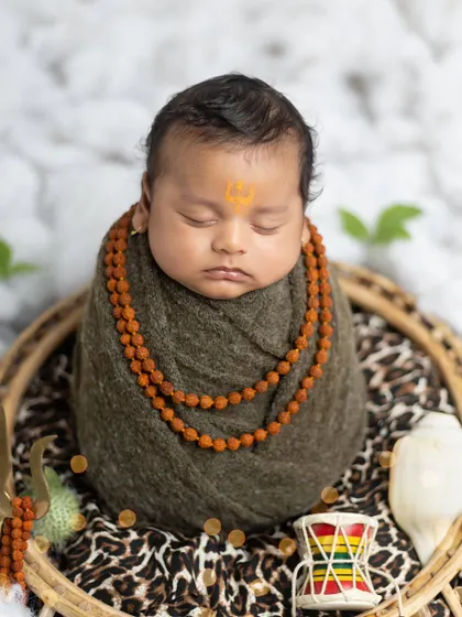 A peaceful close-up of the baby as Mahadev, showing the detail of the rudraksha beads and the serene expression.