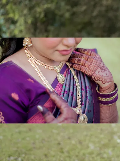 A detailed shot focusing on the bride's stunning gold necklace and intricate mehndi design during her engagement ceremony.