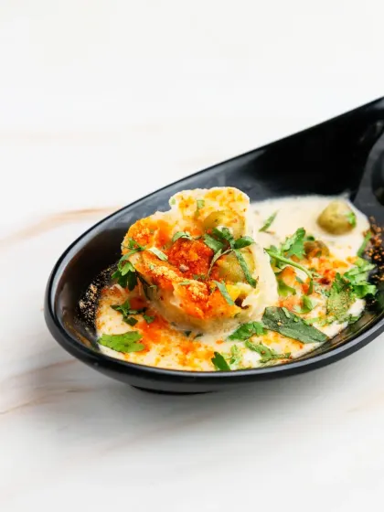A comforting and soulful dish. Our Mini Appam with Coconut Stew features a soft, fluffy rice pancake served in a creamy, mildly spiced vegetable stew, presented in an elegant tasting spoon.