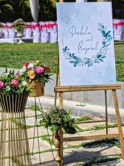 For Deeksha and Prajwal's outdoor event, we designed this watercolor-themed welcome sign placed on a rustic wooden easel. The sign was complemented by floral arrangements in modern metallic vases, blending artistry with nature.