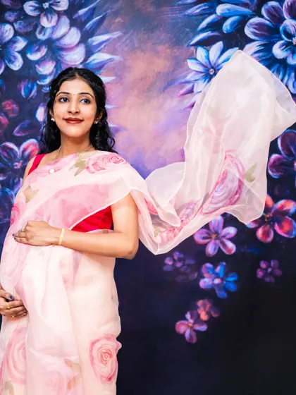 Elegance and grace. This mom-to-be looks absolutely beautiful in a light pink organza saree, creating a soft and dreamy studio portrait.