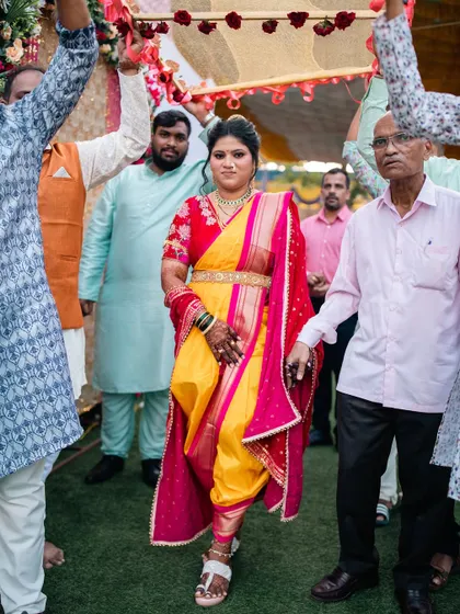 The bride's grand entrance, surrounded by family. The vibrant yellow and red Nauvari makes a powerful statement.