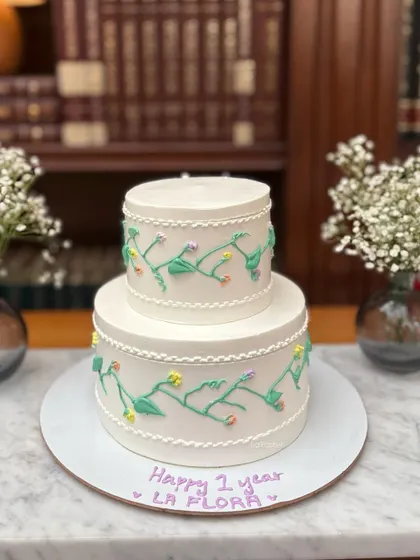 This two-tier cake features delicate, hand-piped vines and flowers for a beautiful, minimalist garden effect. It's perfect for an anniversary or an elegant birthday celebration.