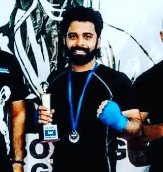 One of our dedicated fighters holding his trophy after a hard-fought competition. This represents countless hours of training and commitment in the gym.