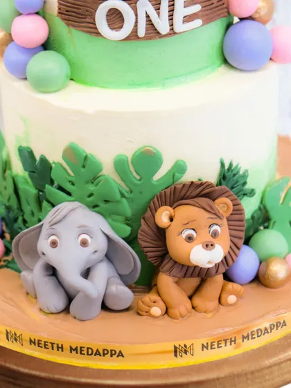 A close-up of the adorable, handcrafted elephant and lion at the base of the safari cake. The detail in their expressions is what brings them to life.