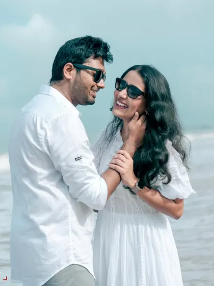 A happy, smiling portrait of a couple on the beach. Dressed in white against the blue sea, this is a classic and timeless look for a pre-wedding shoot.