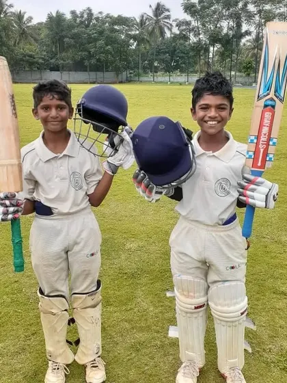 Batting partners ready for action. Two of our young cricketers, fully padded with helmets and bats in hand, represent the future of our academy.