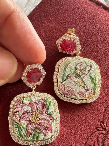 These "Promise of Eden" earrings tell a story across two panels. One features a hummingbird in flight, and the other a blooming lily, both created in stunning micromosaic detail and topped with natural rubies.