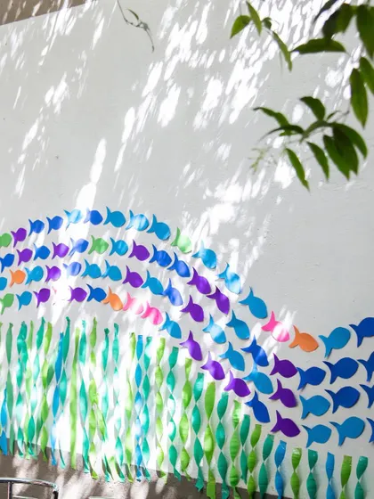 A beautiful wall decoration creating a wave of paper fish. I love using simple, eco-friendly materials to create impactful visuals that transform a space, like this school of fish swimming across the wall.