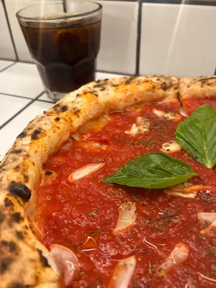 A close-up of our Marinara pizza, paired with a cold drink. The perfect simple pleasure.
