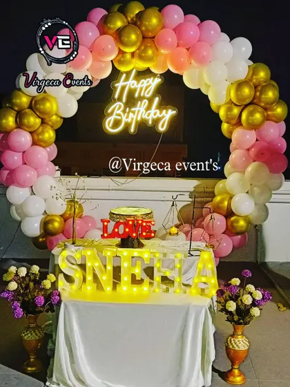 A lovely rooftop birthday decoration with a pink, white, and gold balloon arch.
