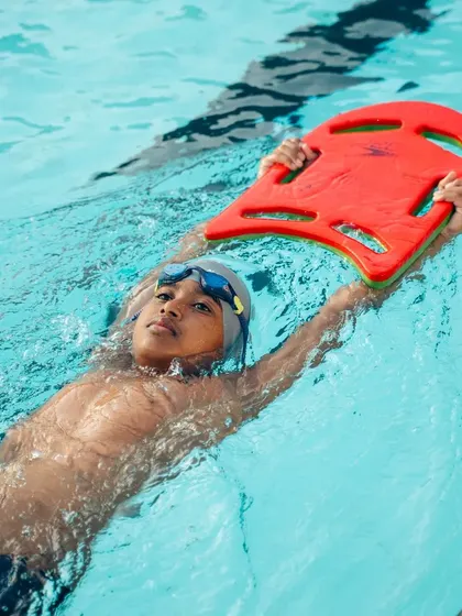 Mastering the back float with a kickboard. This exercise helps children get comfortable on their backs and builds core stability.
