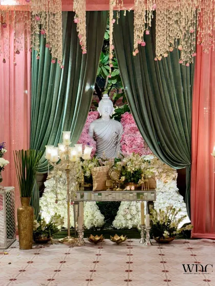 A wider view of the serene Buddha corner, showing the beautiful contrast between the lush green drapes and the soft pink floral backdrop.