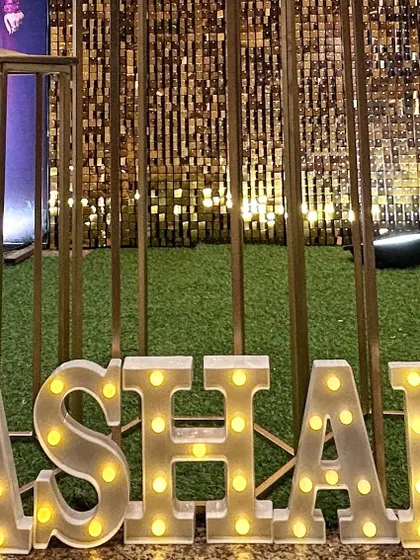 Light-up marquee letters spelling "ASHAN" against a gold shimmer wall. This is a fantastic way to personalize a photo booth area for any event.