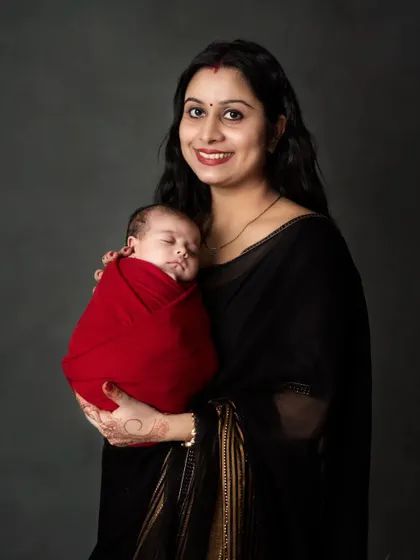 A smiling new mother holds her sleeping baby, a picture of pure contentment.