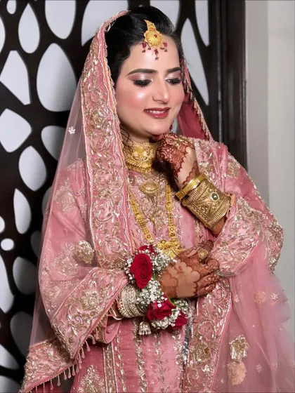 A smiling shot of the client, her happiness radiating. The soft pink makeup and gold jewelry create a look of timeless elegance.