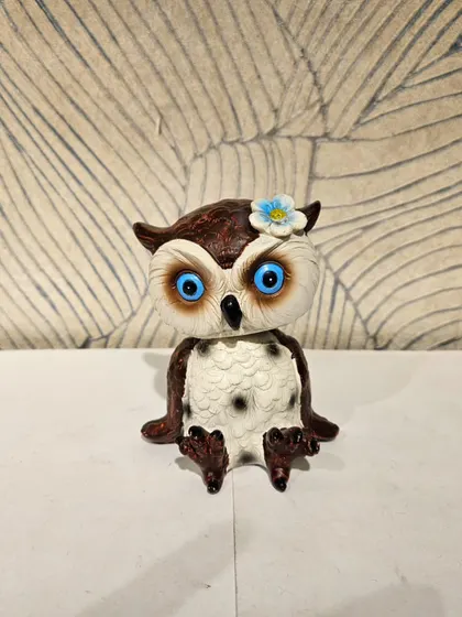 A cute bobble-head owl figurine with big blue eyes. This playful piece adds a fun element to your car dashboard or work desk.