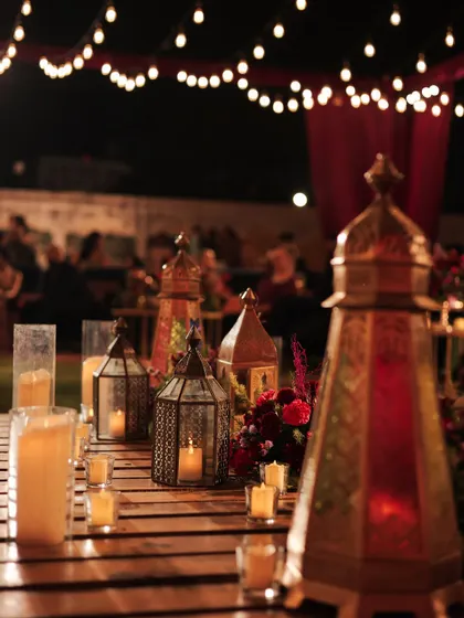 For the picnic-style seating at the Sufi sangeet, the tables were low wooden pallets adorned with Moroccan lanterns, glowing candles, and deep burgundy florals. The look was rustic, moody, and incredibly romantic.