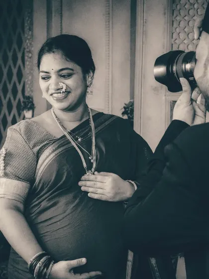 A close-up in black and white that highlights the mother's radiant smile and the intricate details of her traditional jewelry. The focus on light and shadow makes this an intimate and captivating portrait.