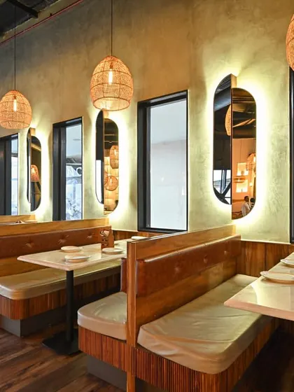 We designed intimate booth seating areas using a combination of wood paneling and upholstered benches. The backlit, pill shaped mirrors add depth and a touch of modern elegance, providing a sense of privacy while reflecting the restaurant's ambient light.