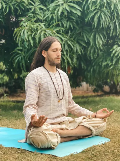 A student meditates outdoors on a yoga mat. We encourage finding moments of stillness and connection with nature throughout the day.