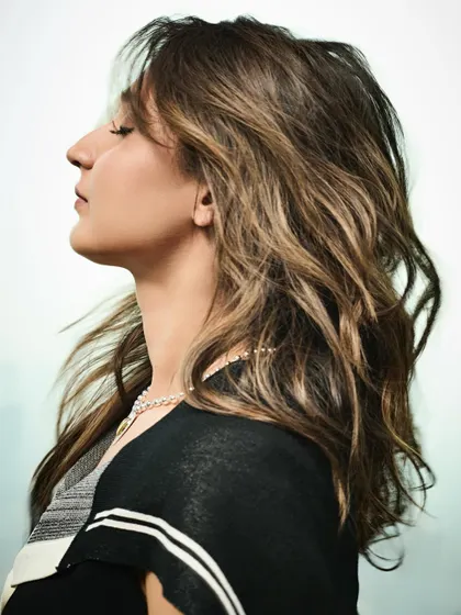 A beautiful profile shot where the movement of her hair adds a dynamic and natural element to the city backdrop.