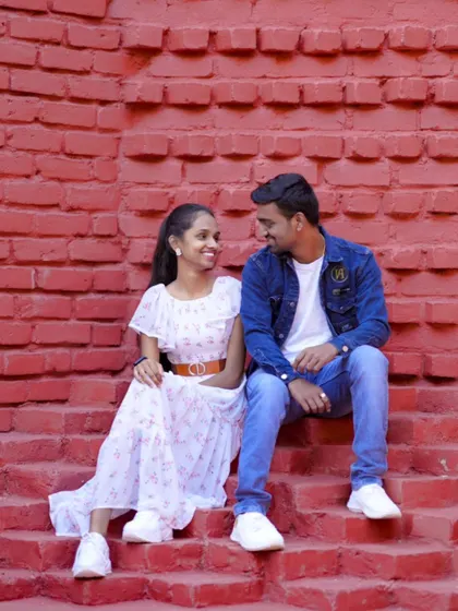 A sweet, candid moment between a couple sitting on red brick steps. Their casual outfits and genuine smiles make this shot special.