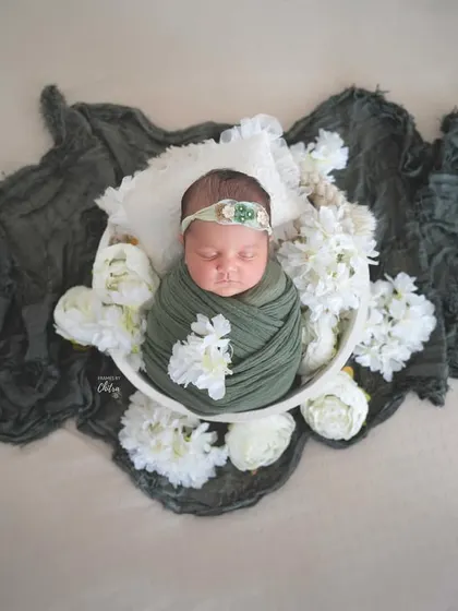 This top-down view shows the full composition, with the dark green fabric creating a beautiful frame around the baby.