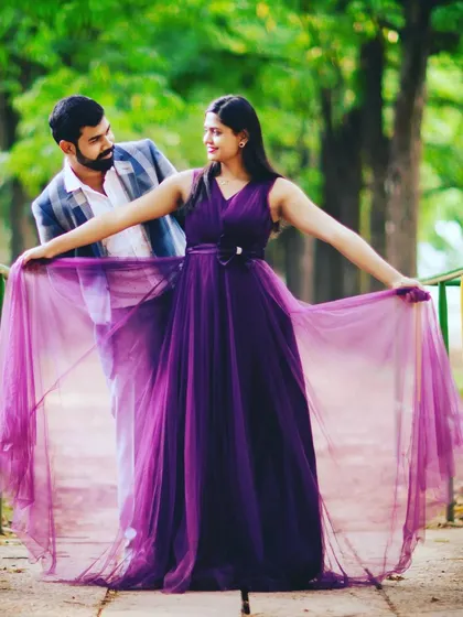 This shot beautifully showcases the sheer, wing-like layers of the purple gown, adding a touch of whimsy and romance to the couple's photoshoot.