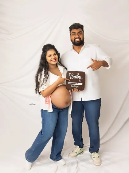 A cute announcement shot with a "Baby Loading" sign. The couple's casual white shirts and jeans create a relaxed and modern vibe.