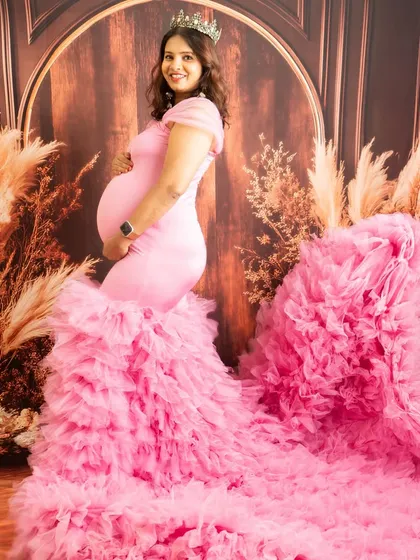 A regal portrait in a pink ruffled gown, complete with a crown. The fabric is expertly tossed to create a dynamic, flowing effect.